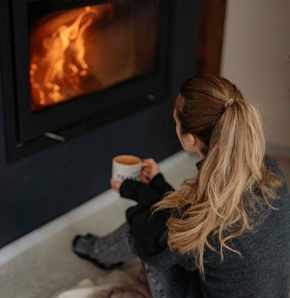 Woman sitting comfortably in front of gas fire